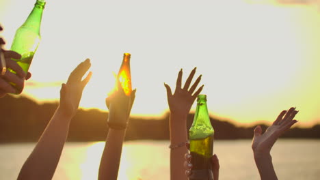 Company-of-young-students-are-dancing-with-hands-up-with-beer.-This-is-perfect-party-at-sunset-on-the-lake-coast.